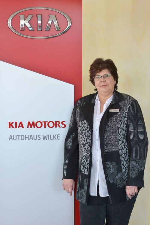 Buchhaltung Renate Wolter vor Kia Motors Logo Wand