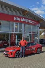 Bild KIA Stinger in rot mit Autohaus Wilke Inhaber Volker Wilke vor dem Autohaus