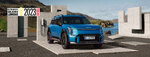 Bild Kia EV9 vor felsiger landschaft auf Parkplatz mit Betonelementen und Ladesäule und Logo "Gewinner goldenes Lenkrad 2023"
