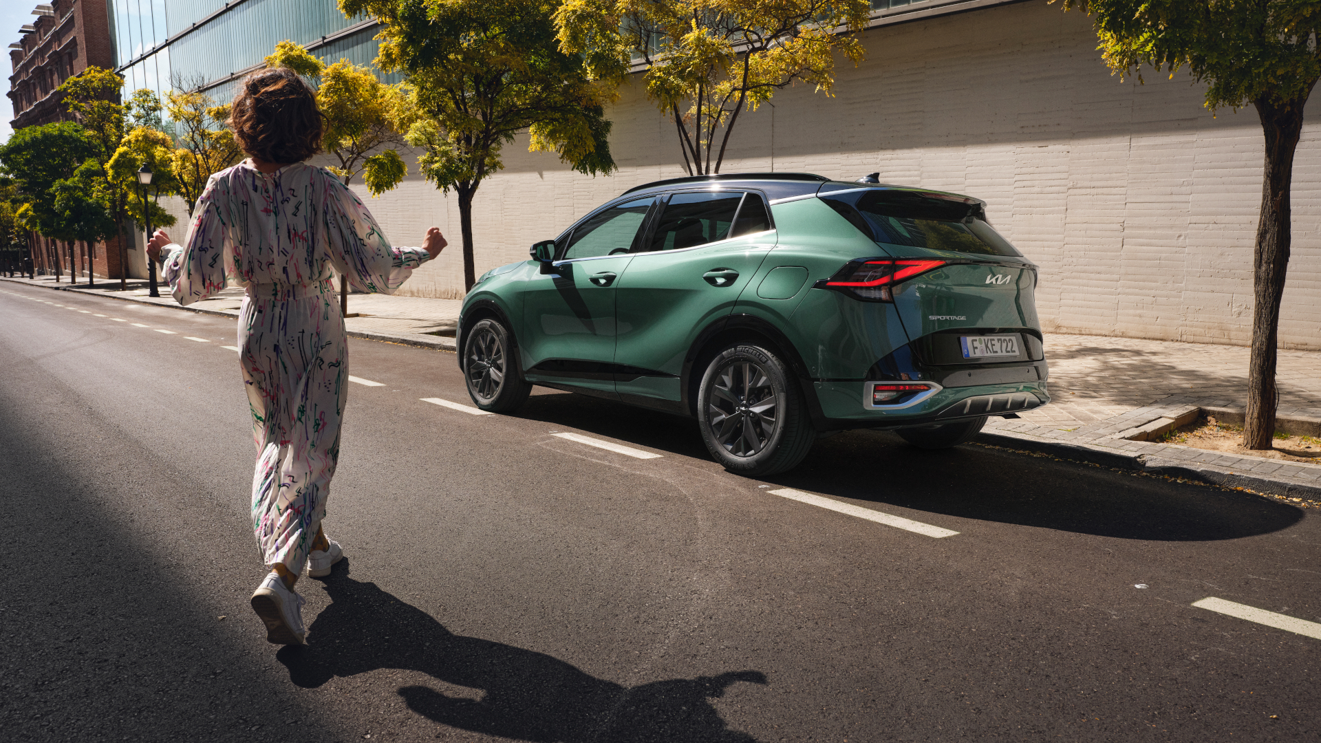 Kia Frau im Kleid, die auf gepartes Kia Modell zuläuft 