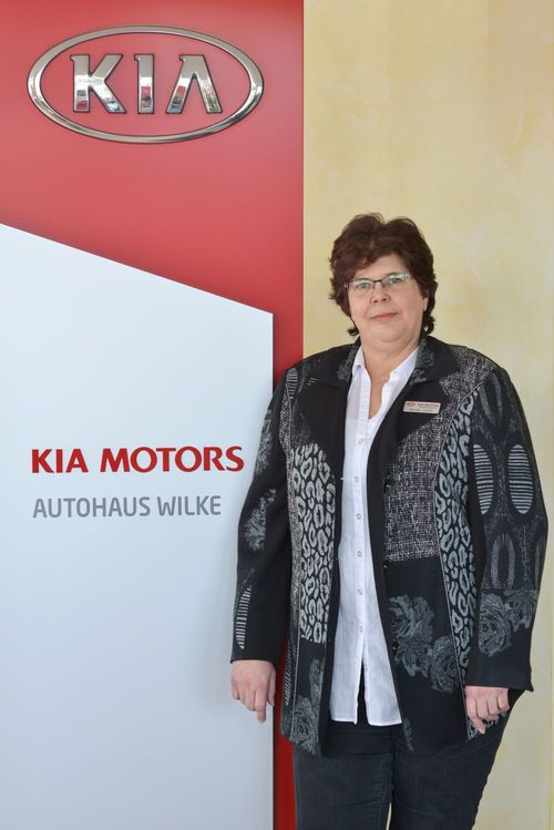 Bild Buchhaltung Renate Wolter vor Kia Motors Logo Wand