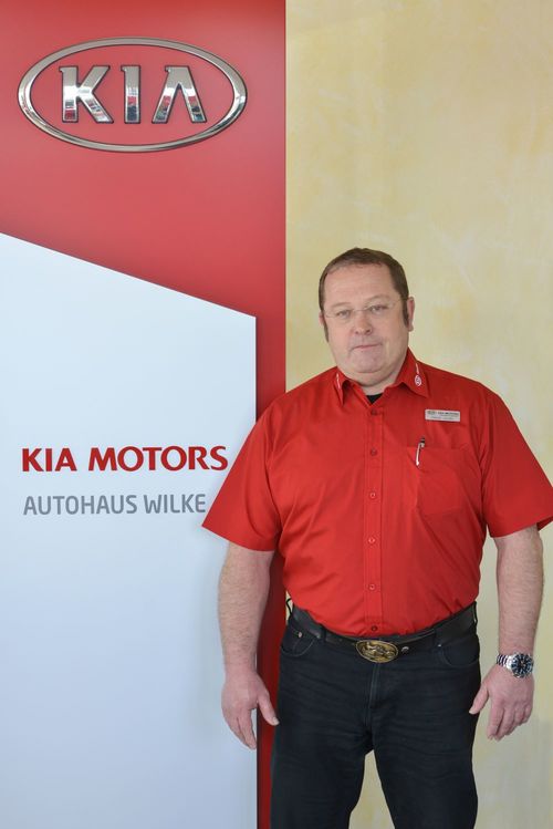 Bild Annahmemeister Bernd Jordan vor Kia Motors Logo Wand